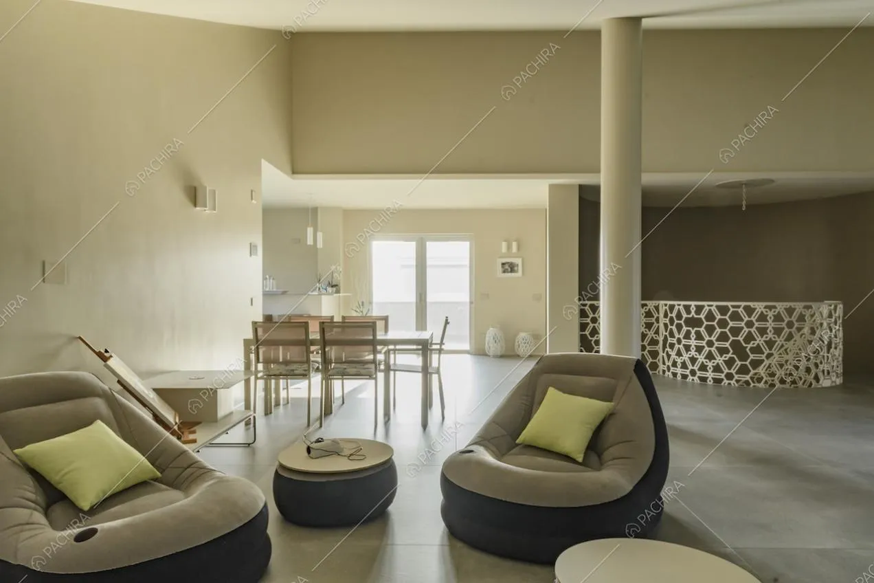 Salotto con poltrone, tavolo da pranzo e porta-finestra per accedere al balcone