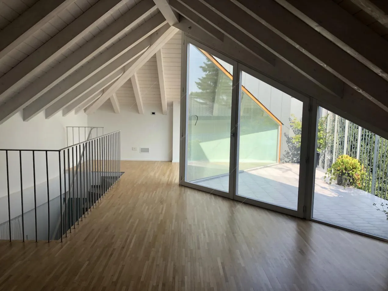 Sottotetto con travi a vista, vetrate e parquet