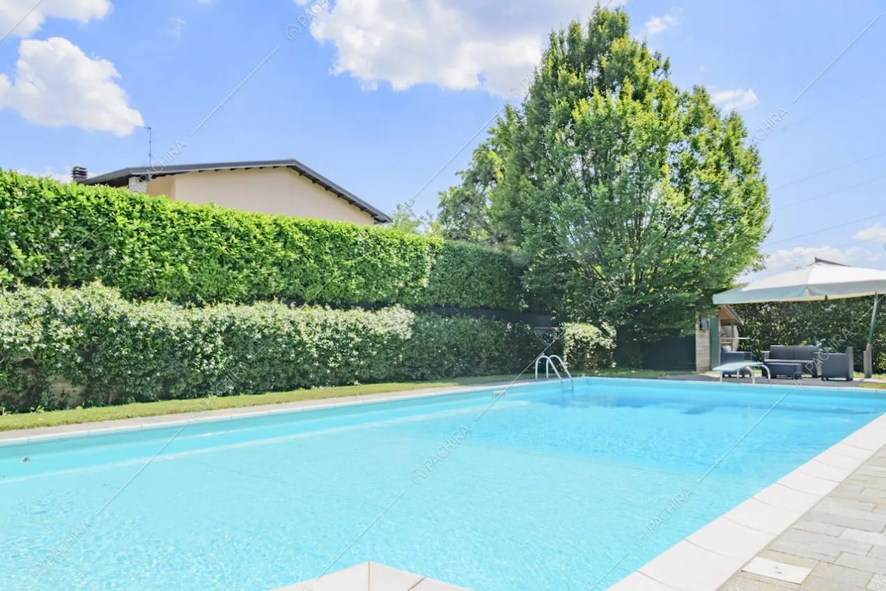 Vista sulla piscina con scaletta e scorcio sull'ombrellone