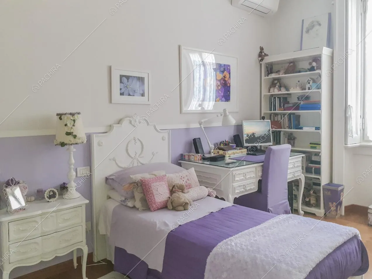 Comodino bianco con abat-jour e scrivania di fianco al letto con testata decorata