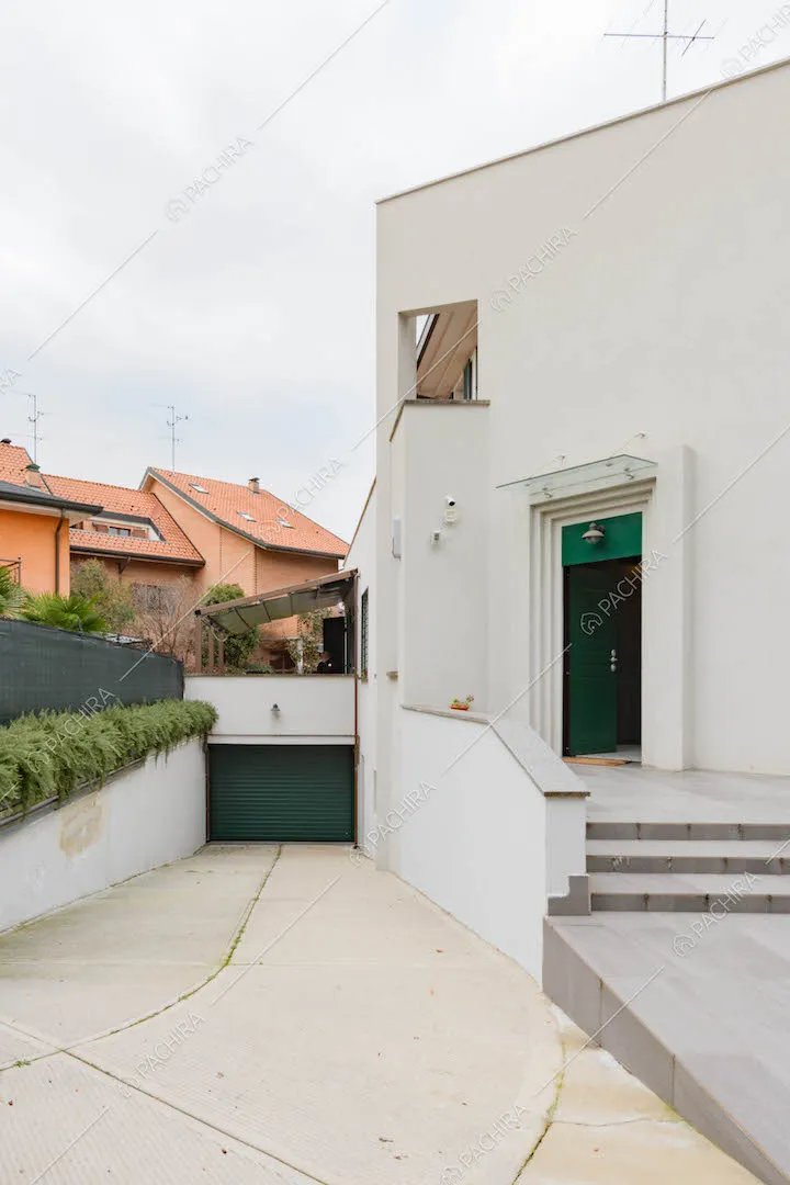 Esterni della location, vista sul garage e sulla porta d'ingresso verde con scalini di accesso