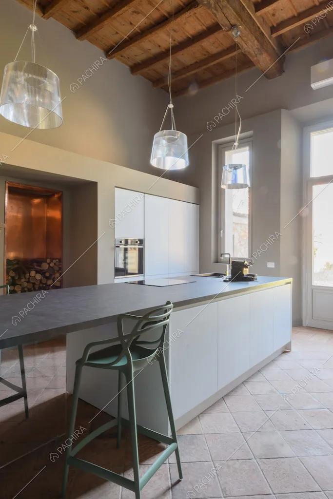 Grande cucina a isola con soffitto a cassettoni, porta-finestra e pavimento in cotto
