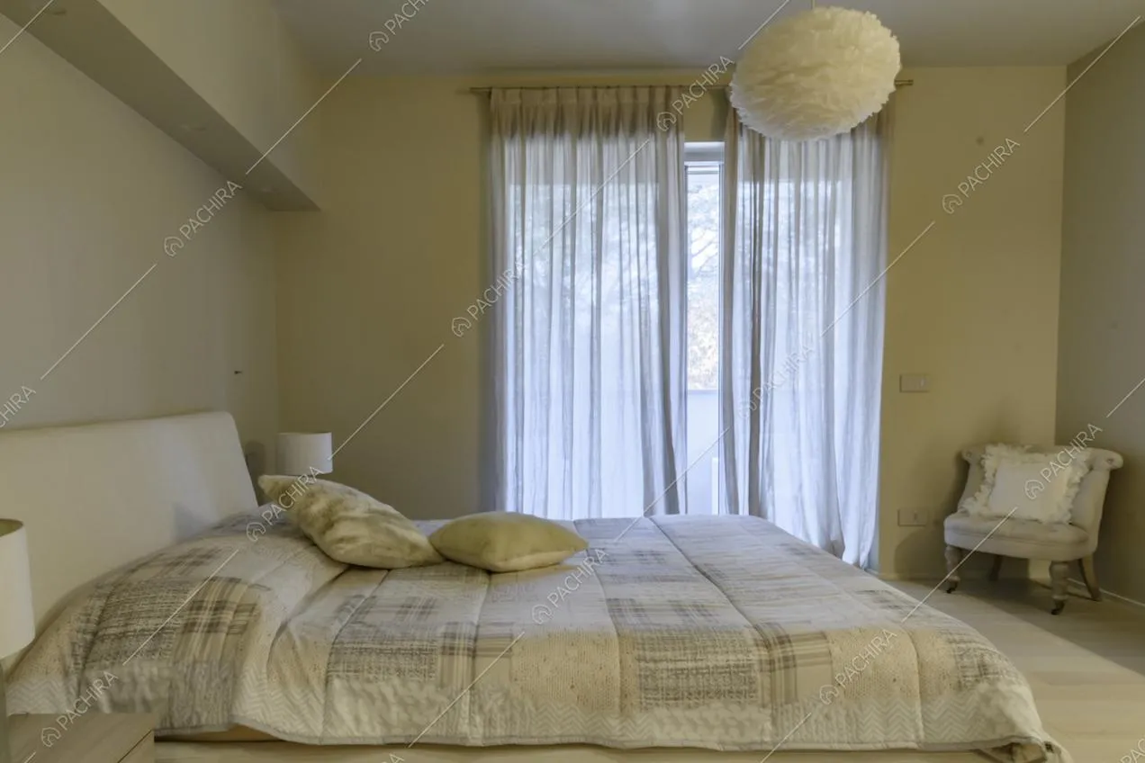 Camera da letto matrimoniale con poltrona e particolare lampadario