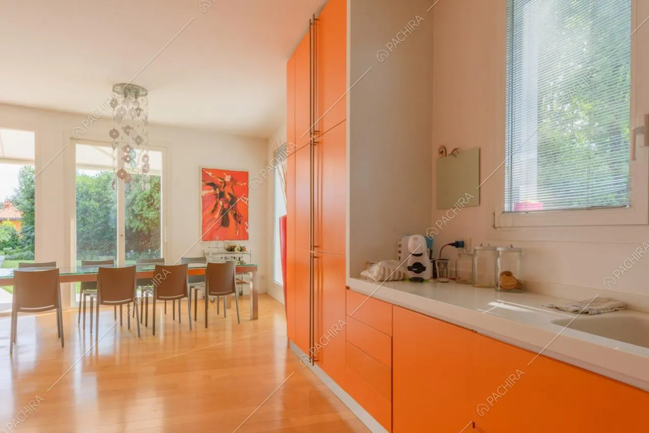 Cucina arancione a parete, riempita di luce naturale dalle porte-finestre