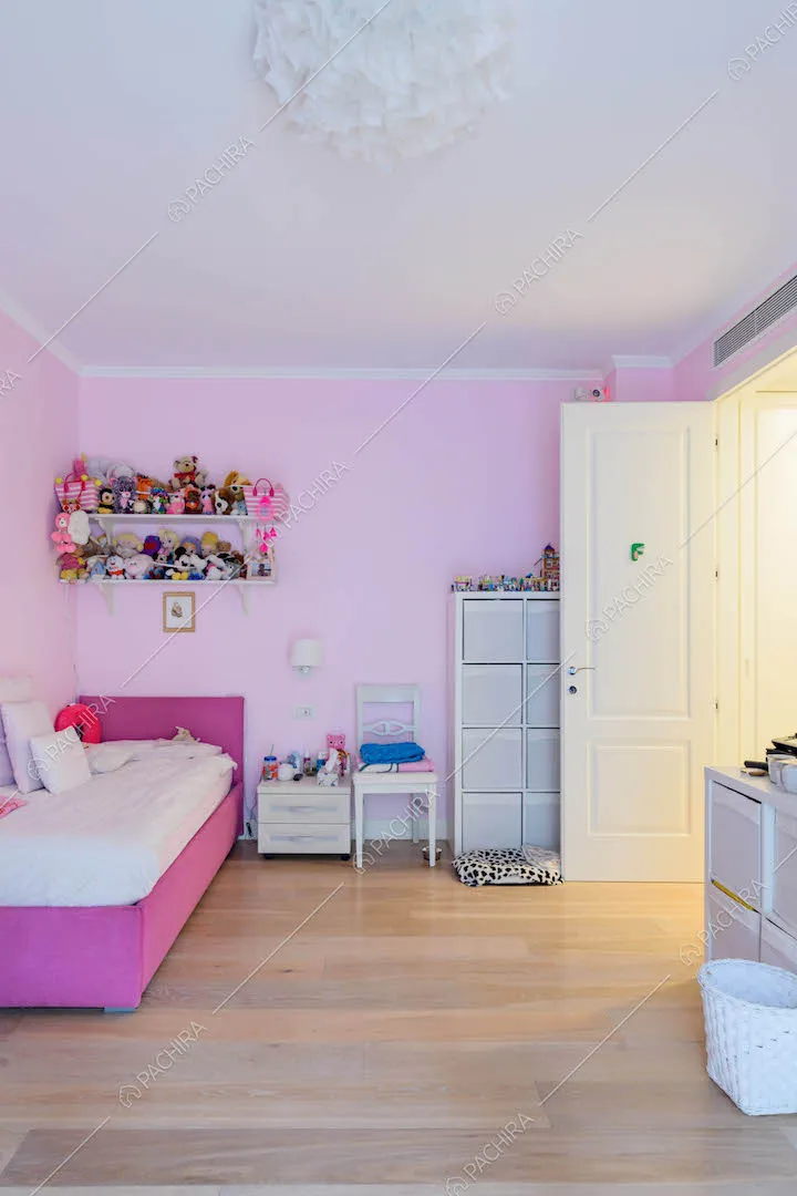 Camera da letto da bambina con pareti rosa e pavimento in parquet