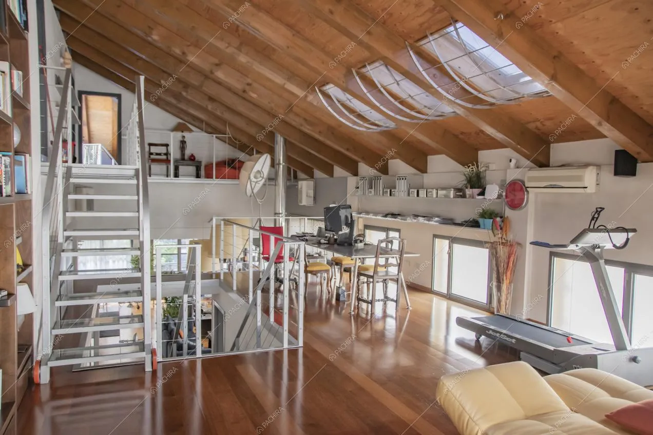 Nel solaio con soppalco, studio con soffitto con travi in legno a vista e lucernari e pavimento in parquet