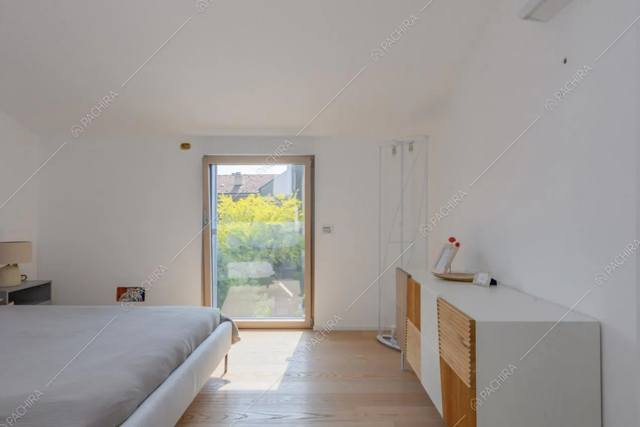 Luminosa camera da letto matrimoniale con vetrata e pavimento in parquet