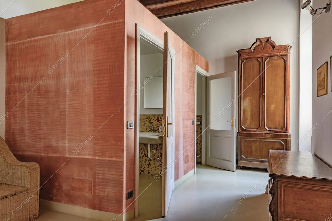 Antibagno con pavimento bianco, pareti rosse e scorcio sul lavandino 
