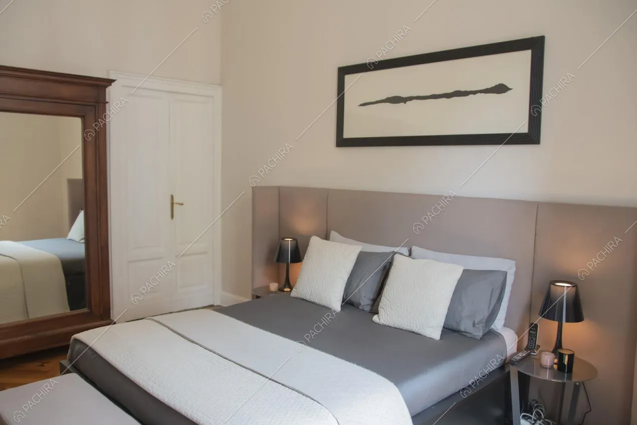 Letto matrimoniale nei toni del grigio e quadro astratto