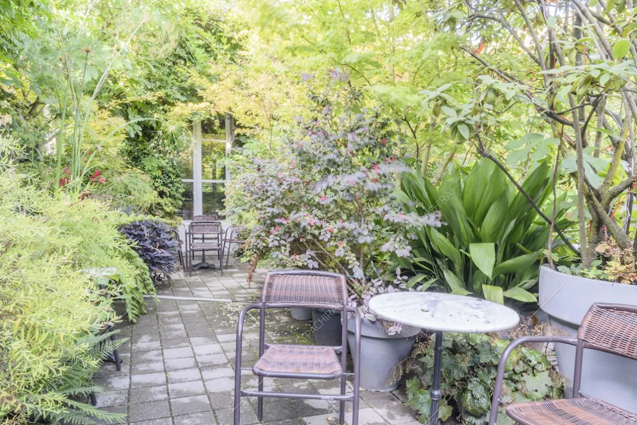 Tavolino tondo in marmo e sedie immersi tra le piante del giardino