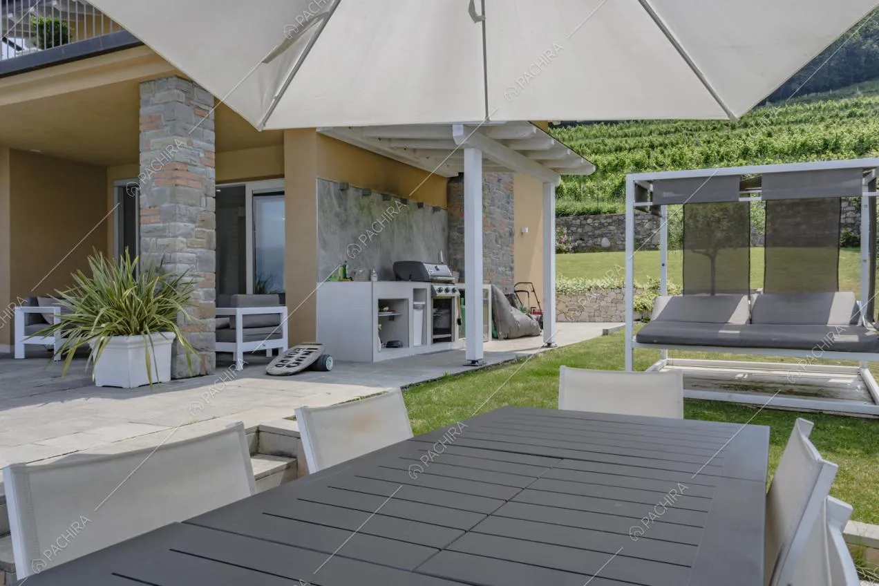 Angolo di giardino con lettini prendisole e tavolo da pranzo