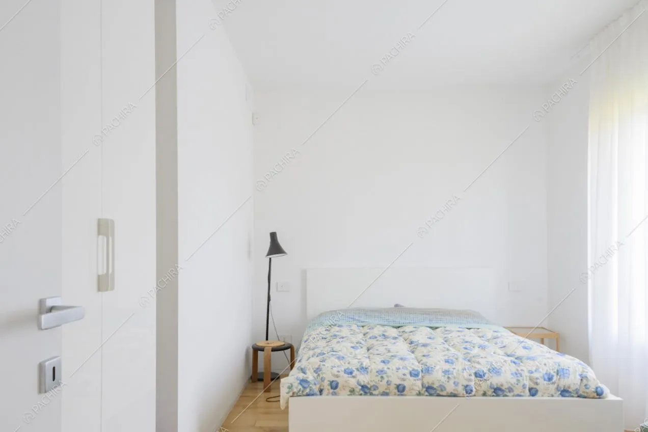Camera con letto, pareti bianche e tende leggere