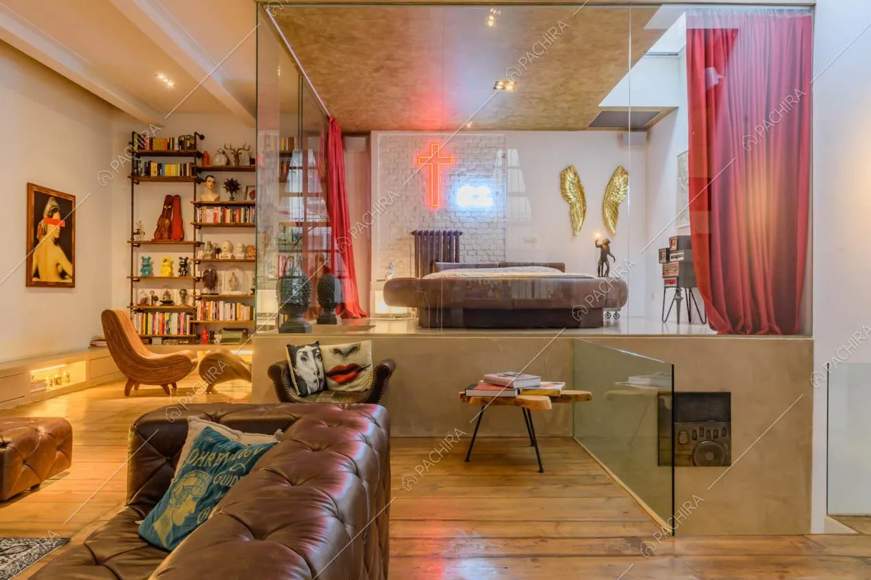 Dal divano marrone in pelle nel salotto con pavimento in parquet vista sulla camera da letto