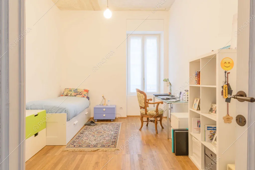 Camera da letto dei bambini con pavimento in parquet, sedia antica e scrivania