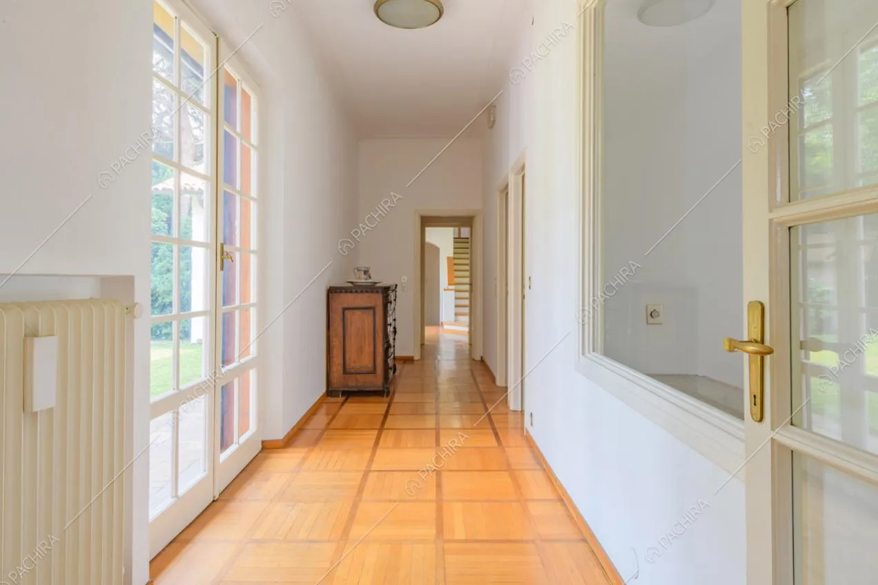 Lungo corridoio con pavimento in parquet e porta-finestra